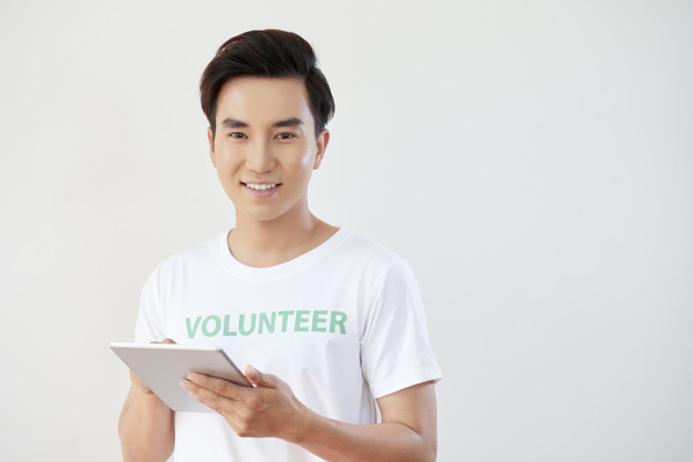 Portrait of Asian young man working as volunteer and using digital tablet in his work isolated on white background